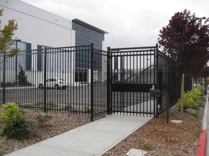 Black ornamental commercial fence with a pedestrian and vehicle gate at a Washington office building